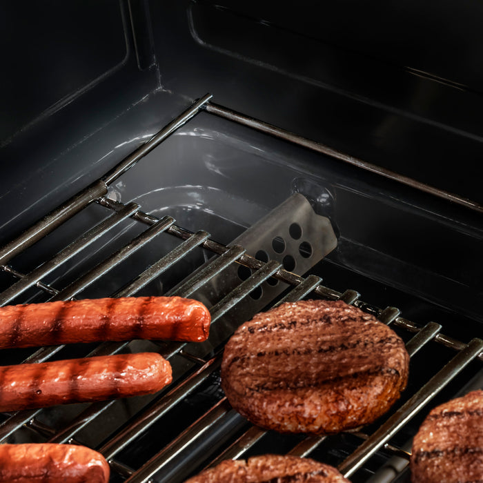 Black grill with sausages and mushrooms cooking on metal grates.