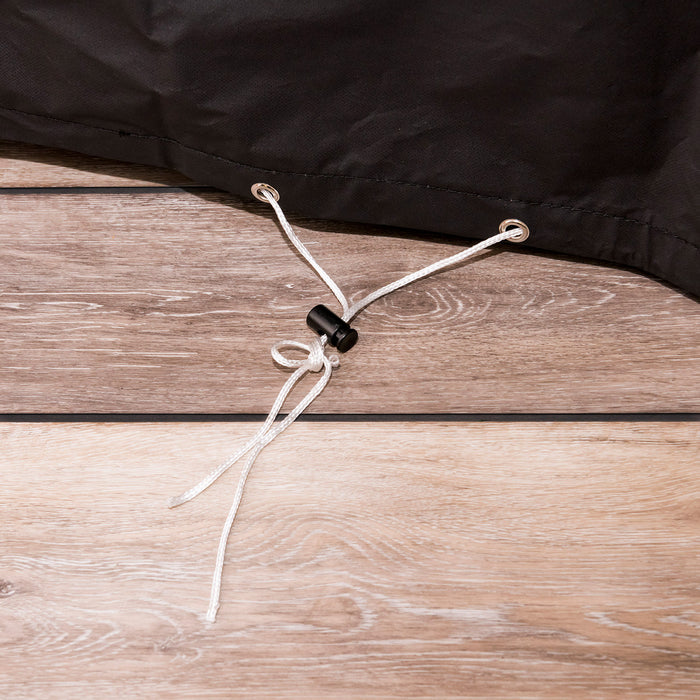 Black drawstring closure with white cord and black toggle on wooden surface.