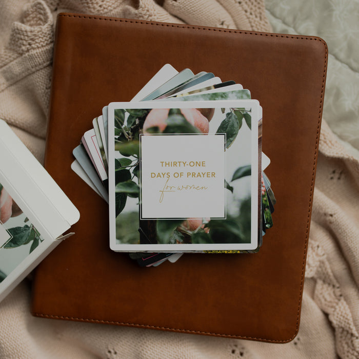 The 31 Days of Prayer cards stacked on a leather bible on a cream colored cloth