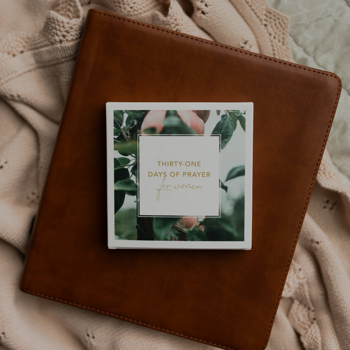 The 31 Days of Prayer cards stacked neatly on a leather bible on a cream colored cloth