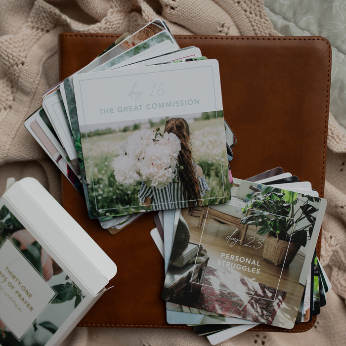 The 31 Days of Prayer cards spread out on a leather bible on a cream colored cloth