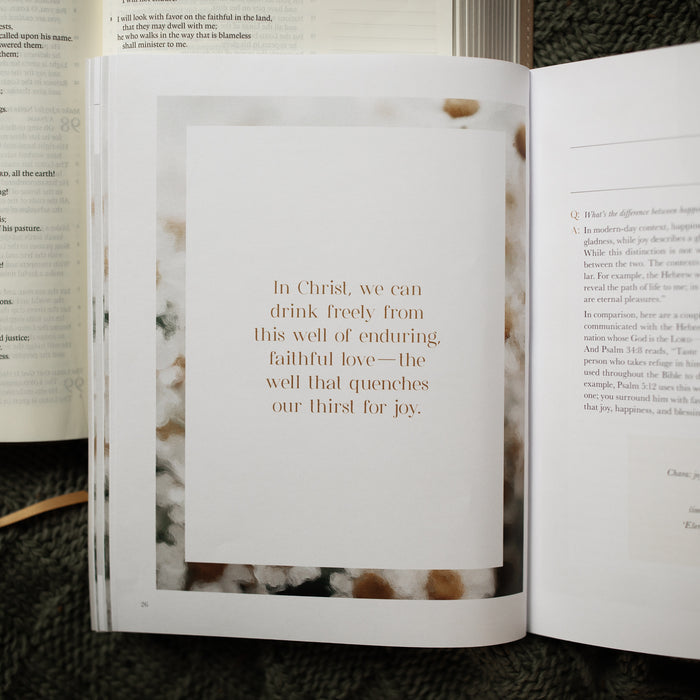 A Joy That Endures bible study opened to the devotional on page 26 laying on an open bible on a green knitted blanket