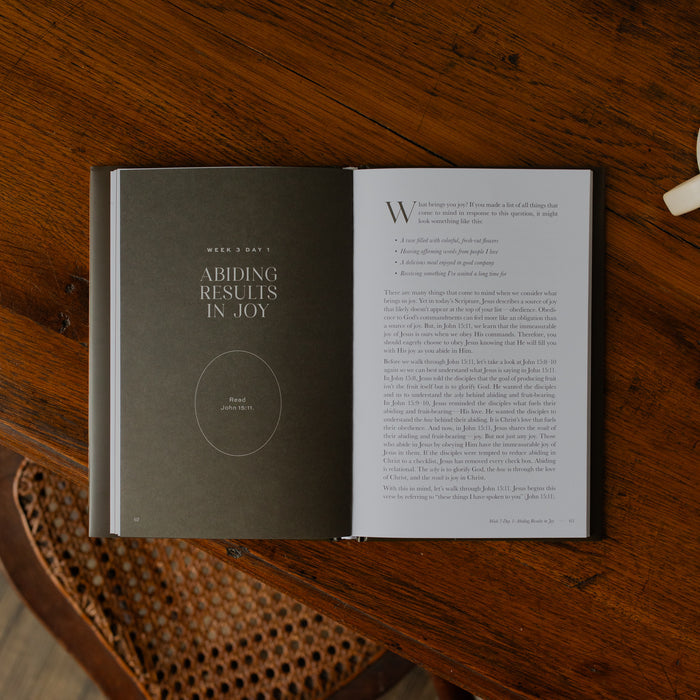 The Abide Hardcover opened to the Week 3 Day 1 Scripture reading page on a wooden table