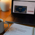 Laptop, notebook, and mug on a wooden table
