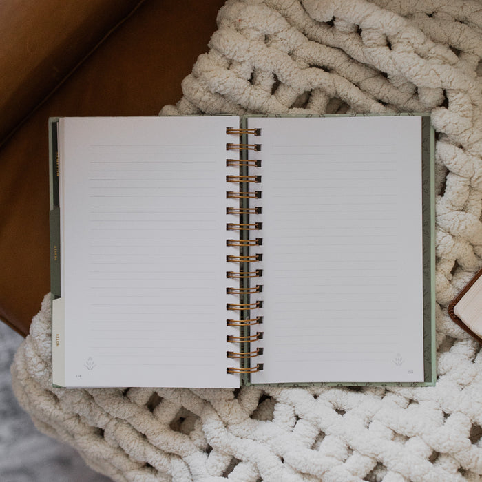 Abide Journal Refresh opened to blank pages on a white knitted blanket on a leather couch