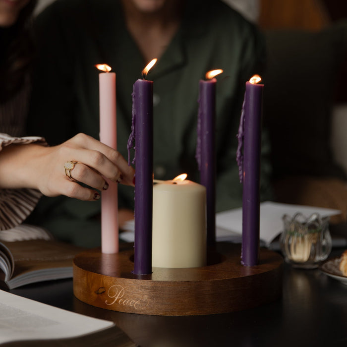 A woman lighting a candle on a dark wooden table