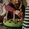 Kids touching a plush wreath on a black table