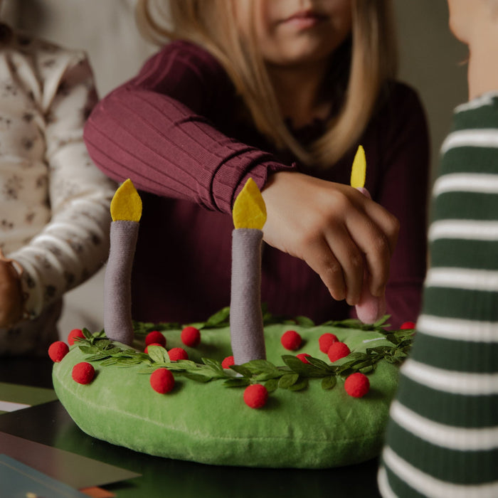 Kids touching a plush wreath on a black table