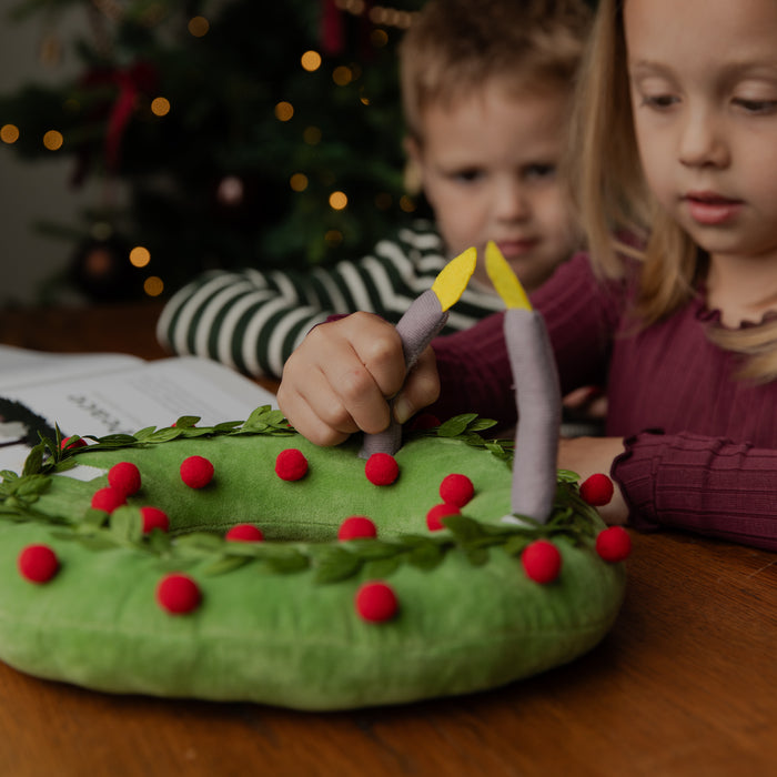 A Kids touching a plush wreath on a table