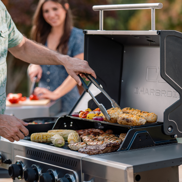 Silver Char-Broil Performance Series gas grill with assorted grilled foods.