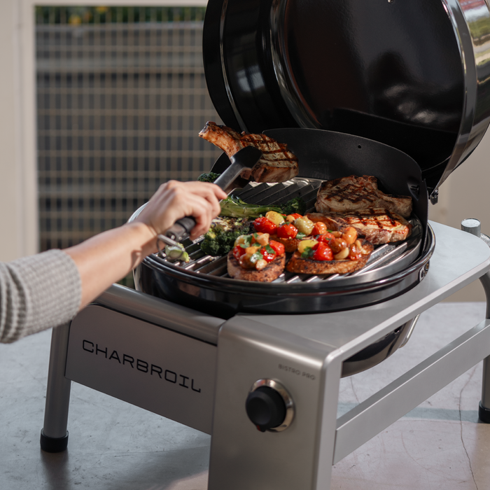 Black Char-Broil Bistro Pro electric grill with charcoal mode, cooking steak and vegetables.