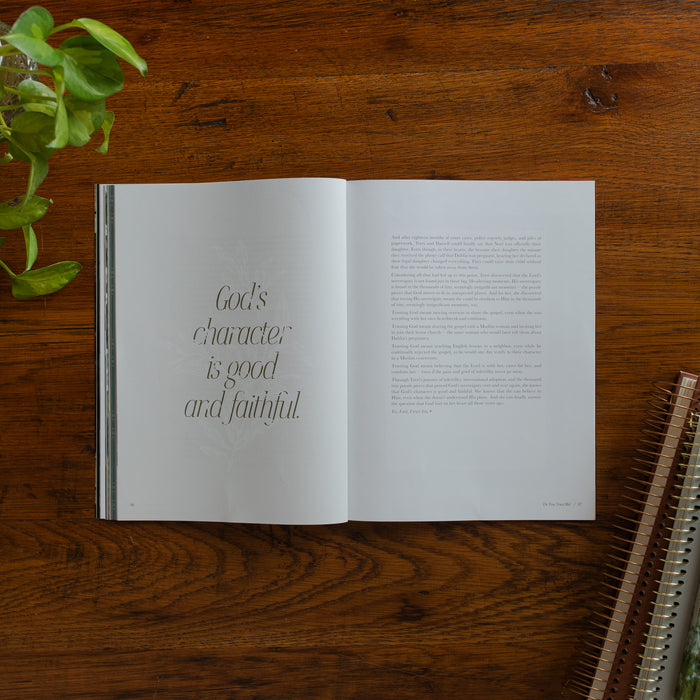 Be Still Issue 40 Magazine opened to the Gods character is good and faithful page on a wooden table near some greenery