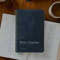 The Better Together Discipleship Guide on an open bible on a wooden table near a white coffee cup