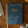The Bible Maps Handbook cover on a wooden table near an open bible and a coffee cup