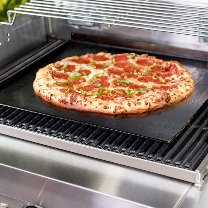 Pizza cooked on a black stone on a grill.