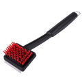 Black grill brush with red bristles and long handle.