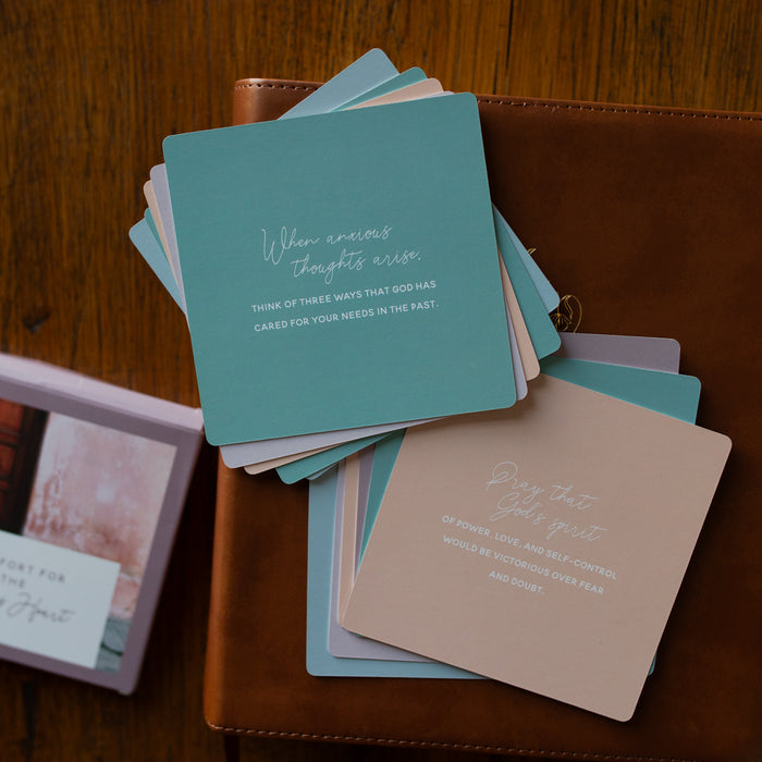 Two stacks of the back of the Comfort for the Anxious Heart Verse Cards stacked on a leather bible