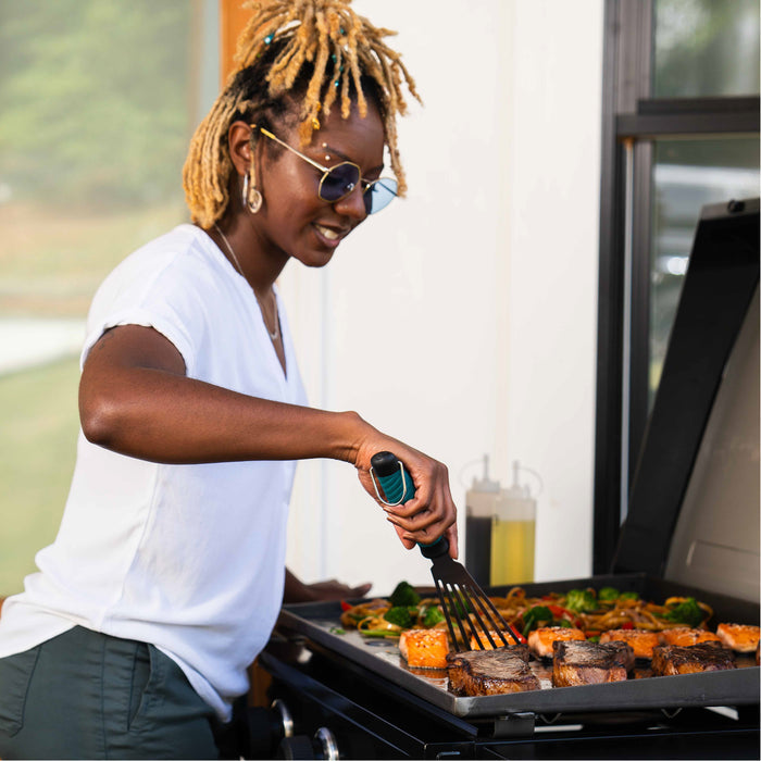 Black electric grill with salmon and vegetables cooking.
