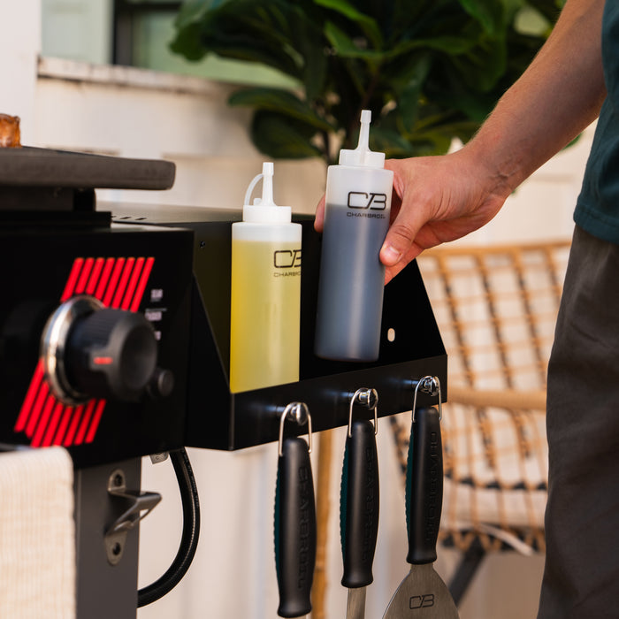 Charcoal Briquettes in white and yellow squeeze bottles on a grill accessory rack.