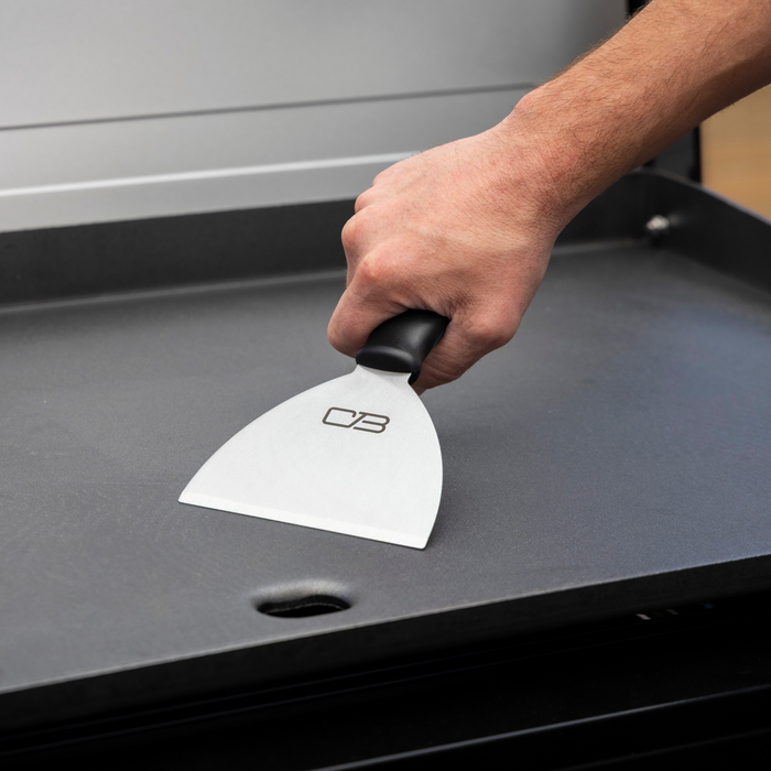 White OXO bench scraper with black handle on a black surface.