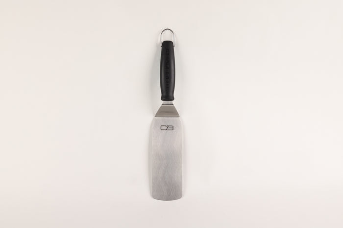 Black-handled metal spatula with "CB" logo on blade.