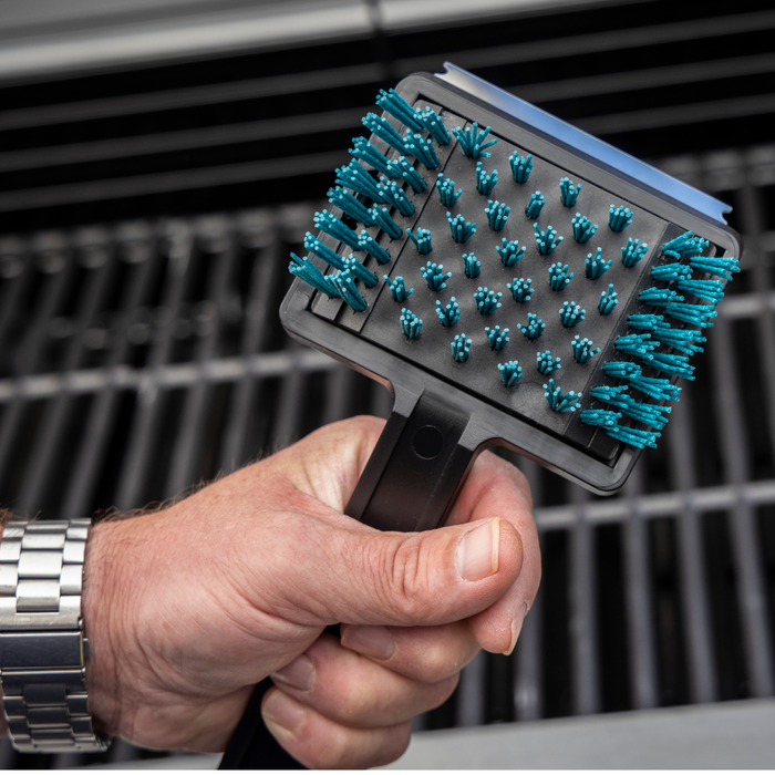 Black and teal pet grooming brush held by hand.
