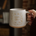 A woman holding a coffee cup with the words Corum Deo on it