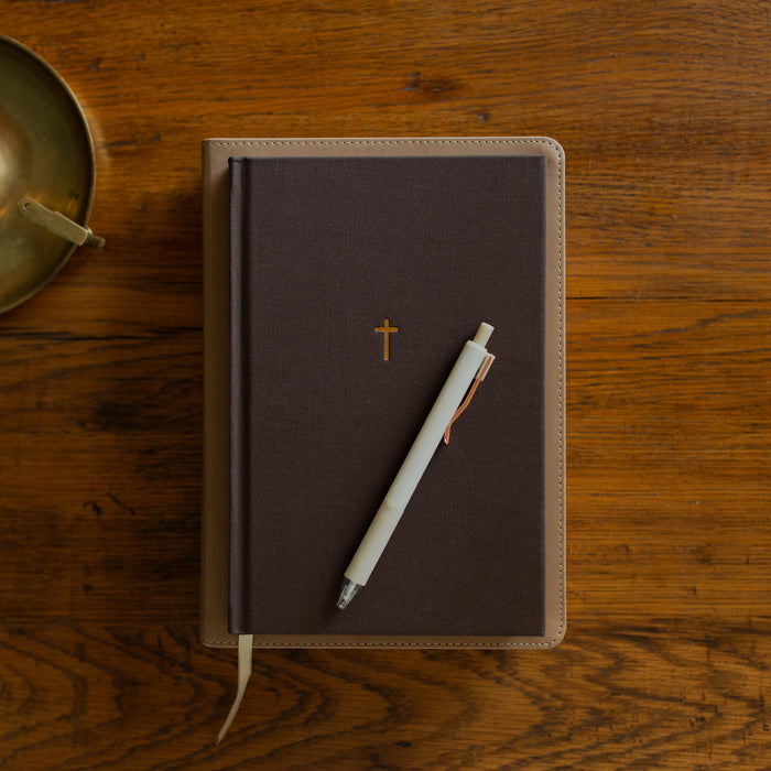 The Cross Journal cover on a bible on a wooden table