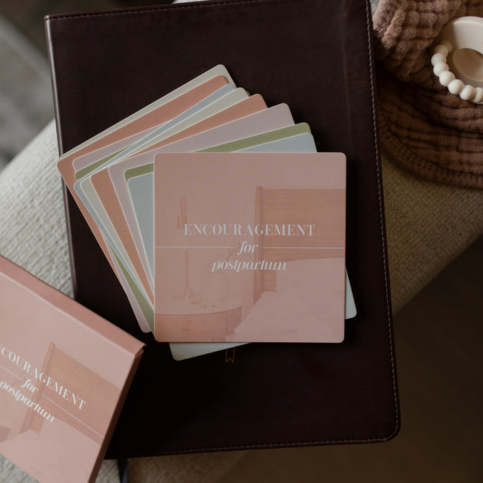 Stack of cards with 'Encouragement for postpartum' text on a dark surface.