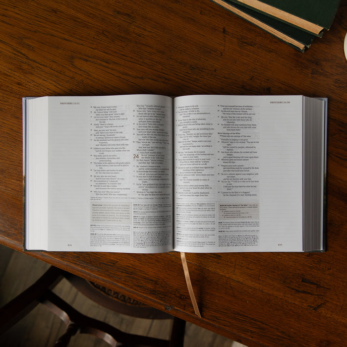 Open Bible on a wooden table with a closed book next to it