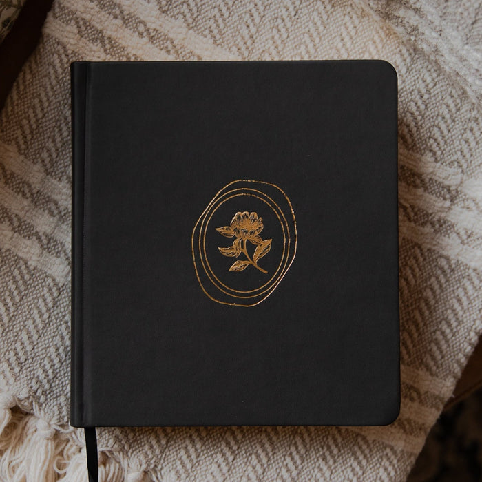 Black bible with a gold emblem on a textured blanket