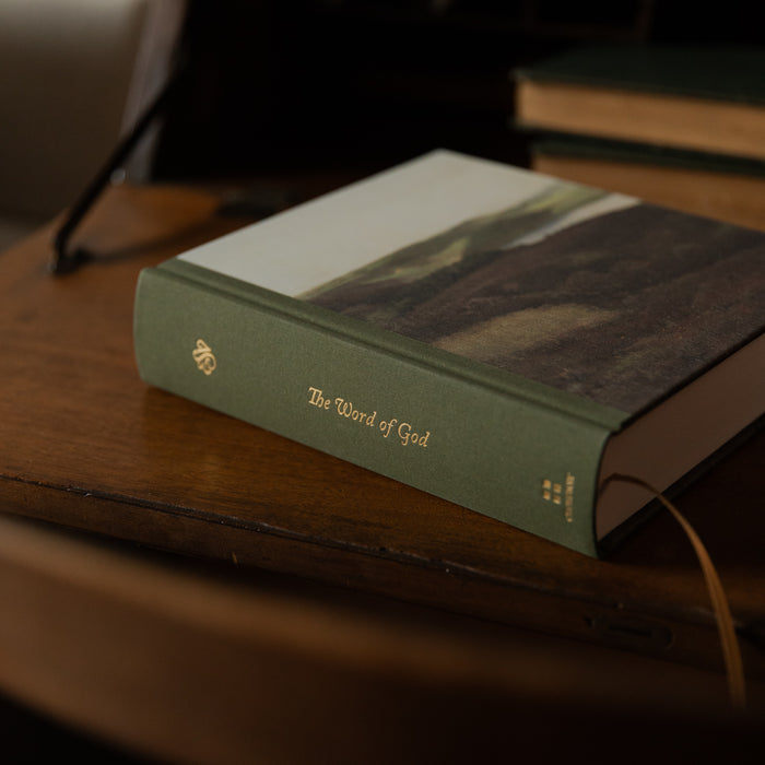 Green Bible titled 'The Word of God' on a wooden surface