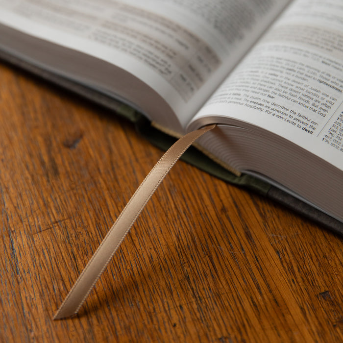 Open Bible on a wooden surface with a ribbon marker.