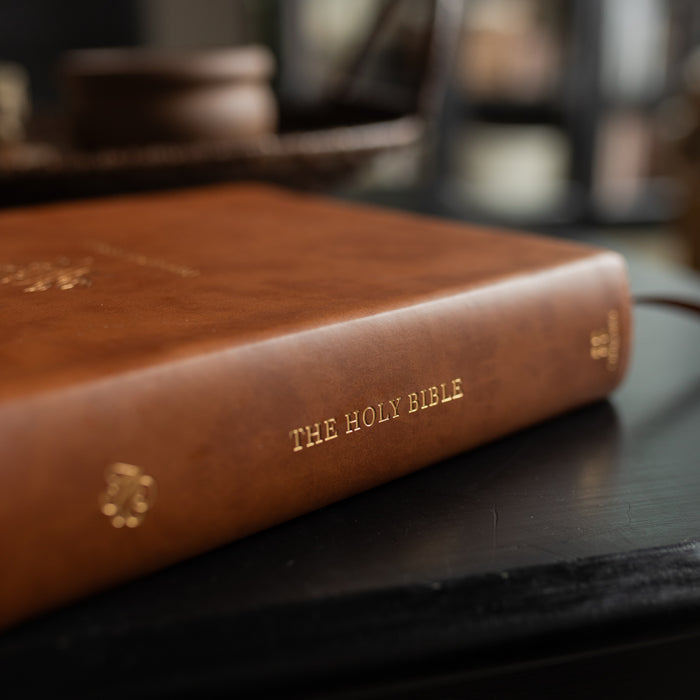 The spine of A leather ESV bible cover on a dark wooden table