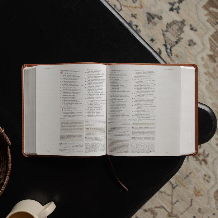 A leather ESV bible opened to the Psalms pages on a dark wooden table