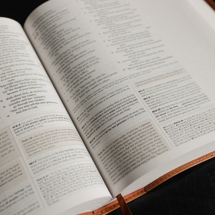 Up close of A leather ESV bible opened to the Psalms pages on a dark wooden table