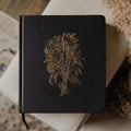 Black Bible with a gold embossed design on a textured surface