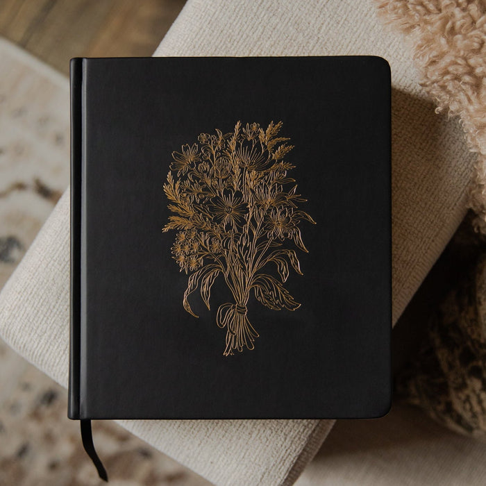 Black Bible with a gold embossed design on a textured surface