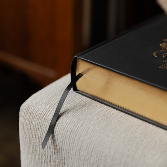 Black leather-bound bible with gold interior on a textured surface