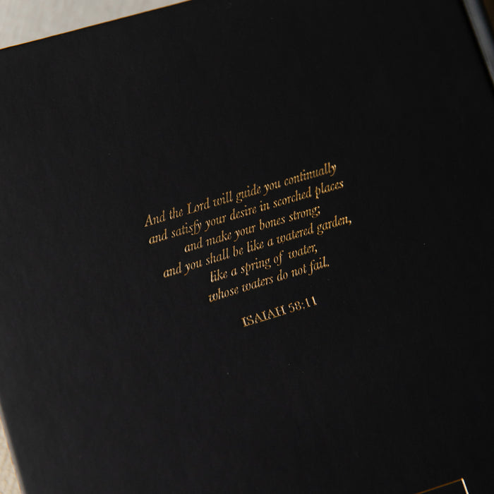 Black bible with gold text on a dark background