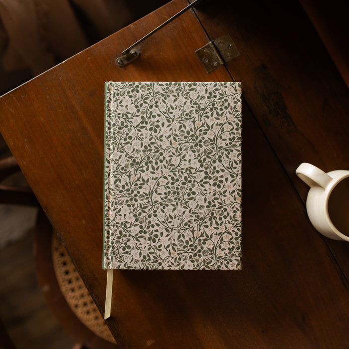 Floral-patterned notebook on a wooden surface with a blurred background