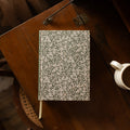 Floral-patterned notebook on a wooden surface with a blurred background
