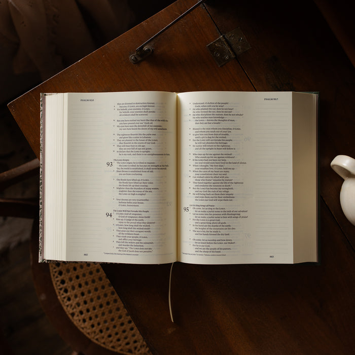 The Clover Journaling Bible opened on a wooden table with a teacup in the corner