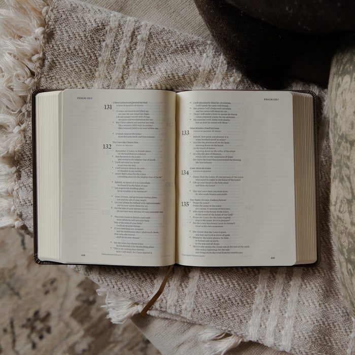 The Holy Bible opened to the Psalms section on a blanket on a couch