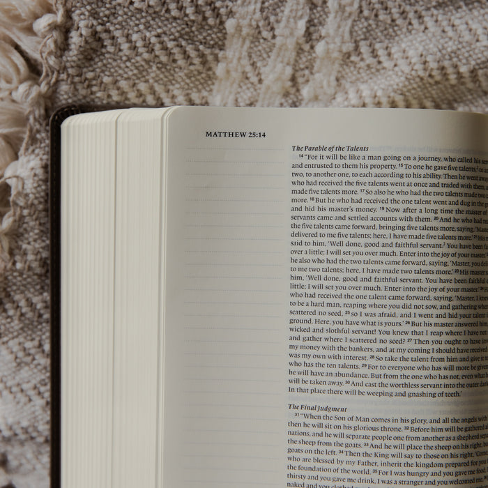 The Holy Bible up close and opened to the Matthew section on a blanket on a couch