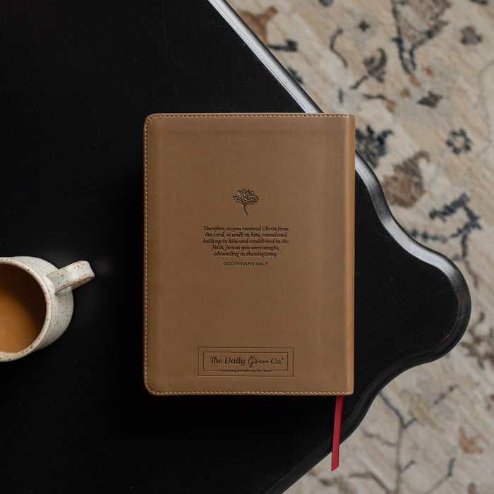 The back of the ESV Single Column Journaling Bible on a black wooden table near a coffee cup