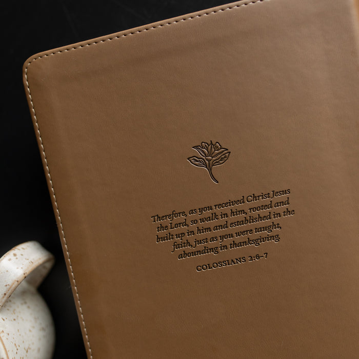 The back of the ESV Single Column Journaling Bible up close on a black wooden table near a coffee cup