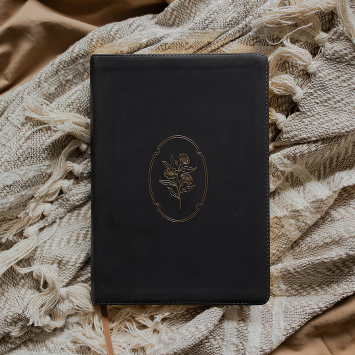 Black bible with gold engraved cover on a textured blanket