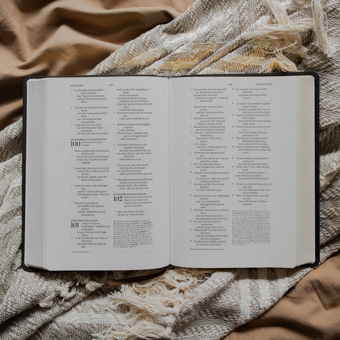 An open bible to Psalms 100 on a textured blanket