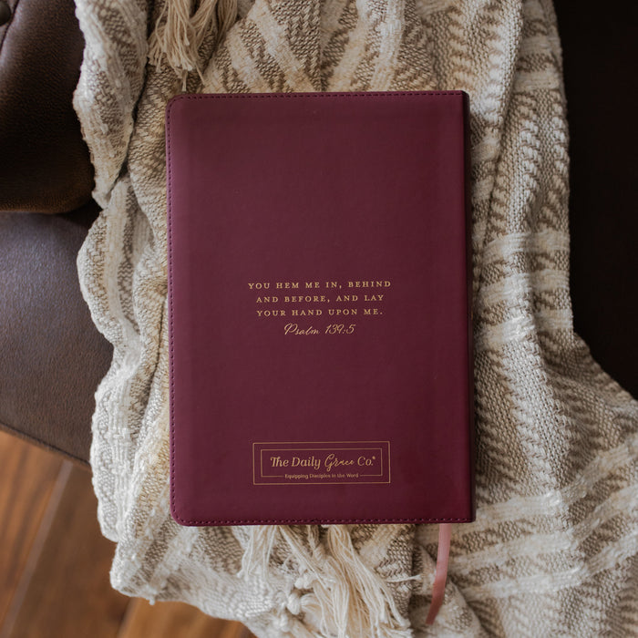 Maroon bible back with gold text on a textured blanket